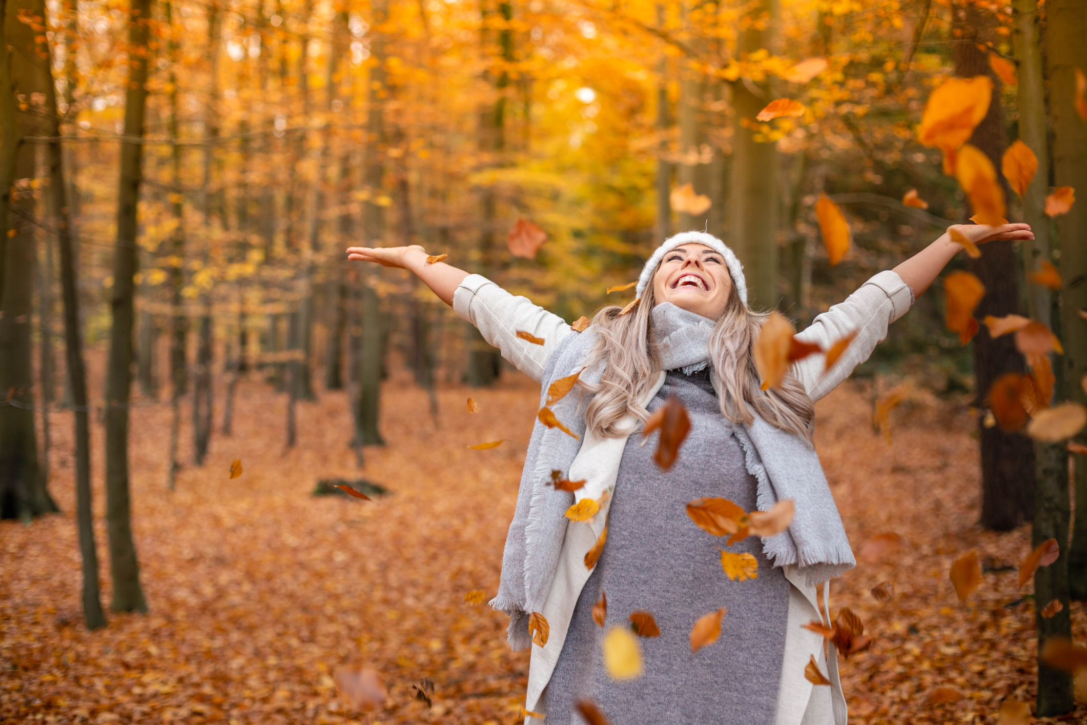 Frau-wirft-Blätter-im-Herbstwald